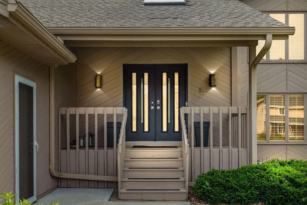 Front porch and black double doors of the Burnsville home, lit at twilight
