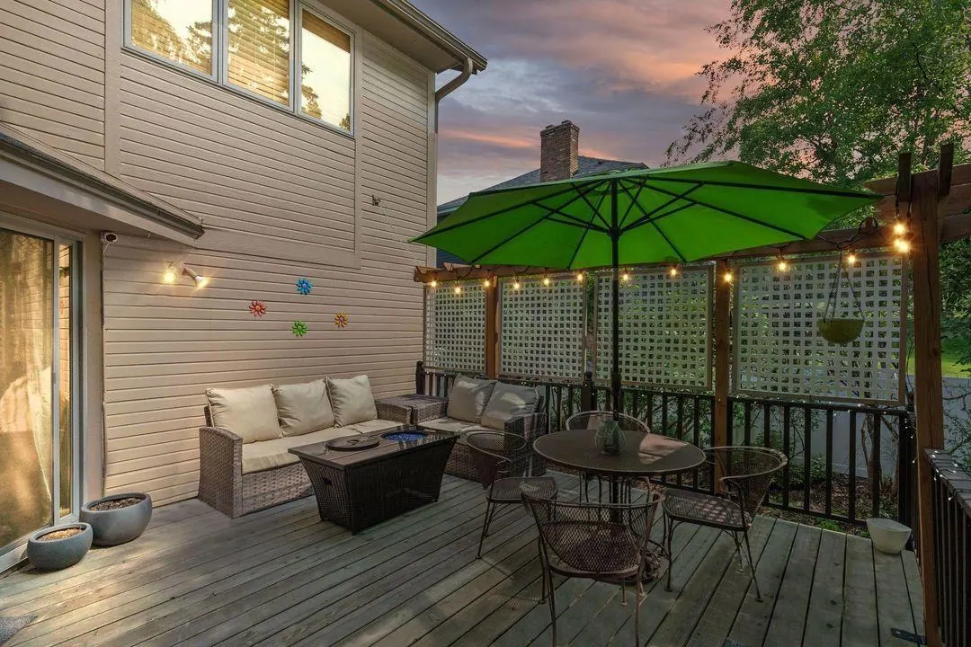 Back deck at dusk with string lights, outdoor sofa and a green umbrella