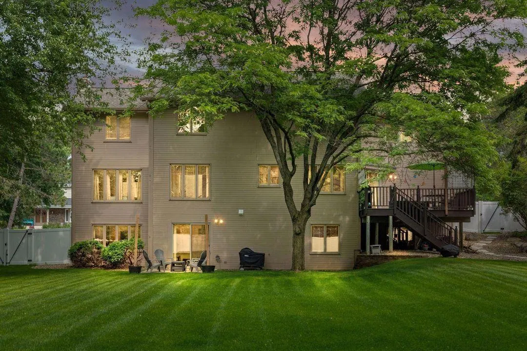 The back of the Twin Cities Living Assistance home in Burnsville at dusk, windows lit behind a big maple tree