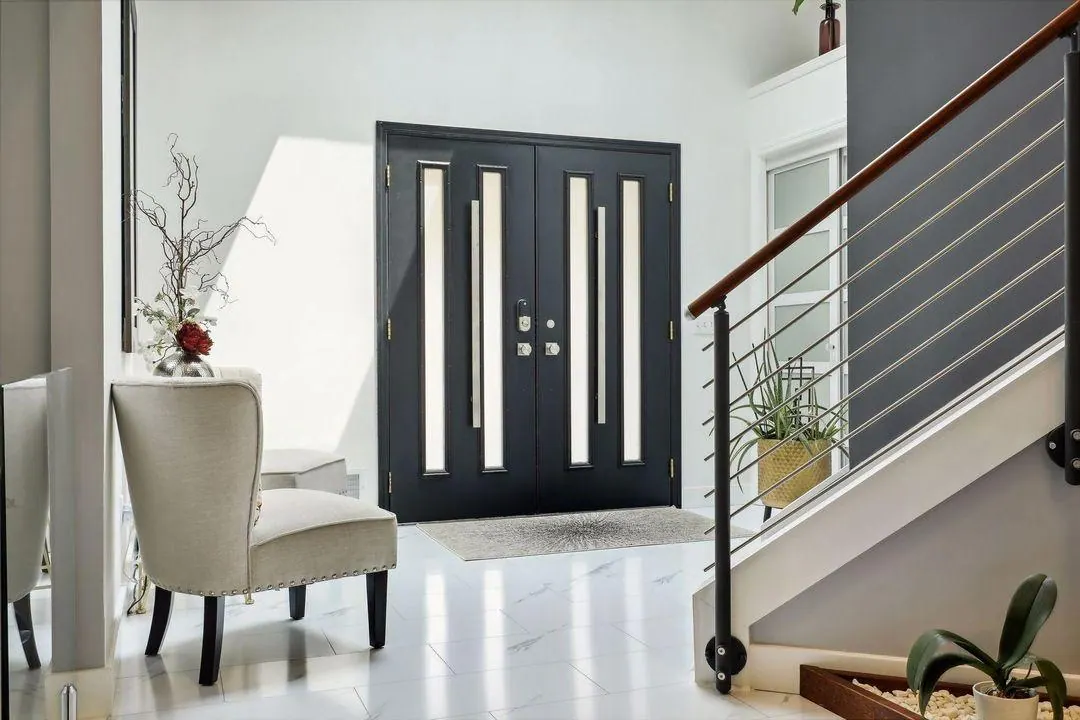 Bright foyer with white tile, double doors and an upholstered chair