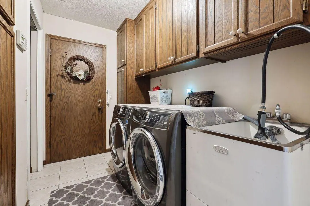 Laundry room with front-loading washer and dryer and wood cabinets in the Burnsville home