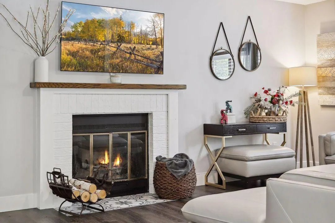 Family room fireplace with stacked firewood, mirrors and a white sofa
