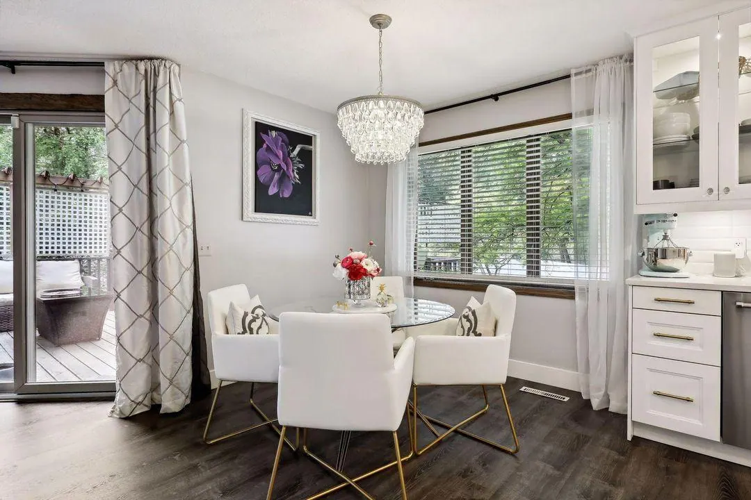 Breakfast nook with a round glass table and white chairs beside the kitchen