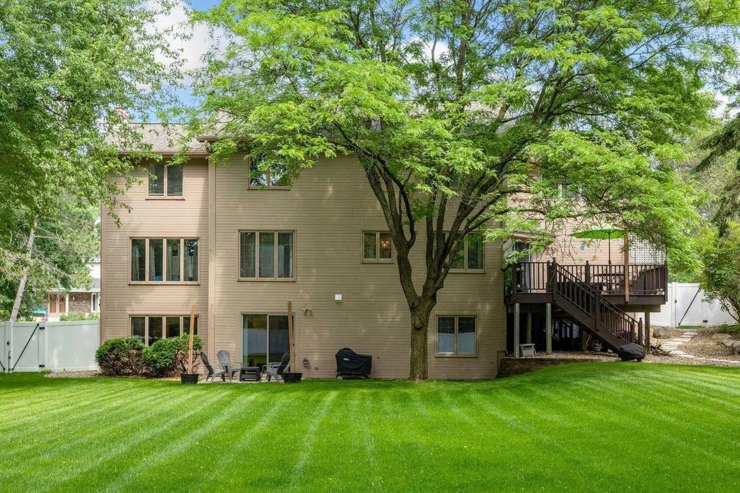 Wide striped back lawn behind the two-story Burnsville home, with mature trees