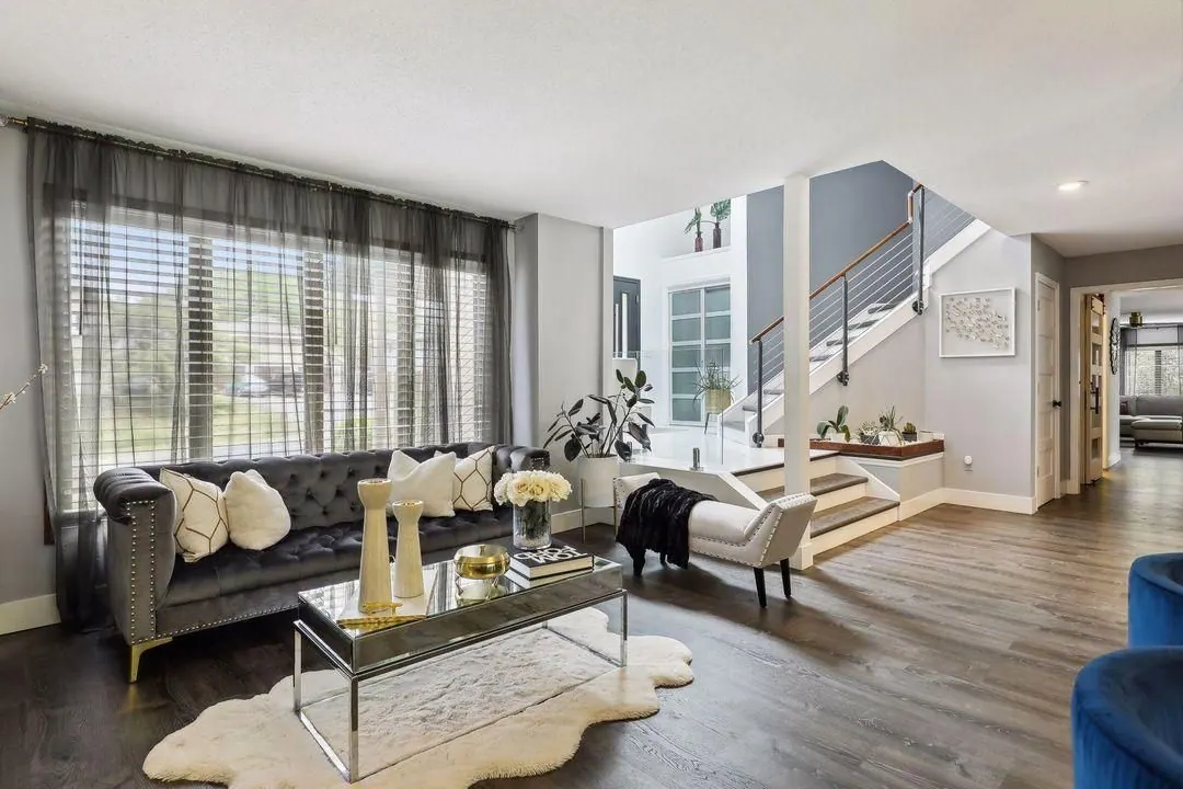 Living room with a gray tufted sofa, white rug and tall windows