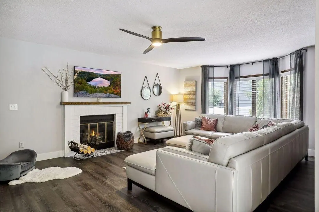 Family room with a lit fireplace, white sectional and wide windows in the Burnsville home