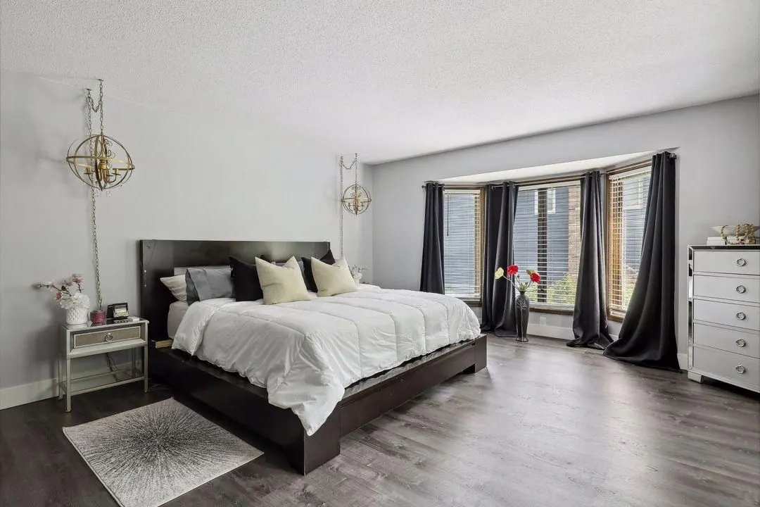 Bright bedroom with a dark wood bed, white bedding and a bay window