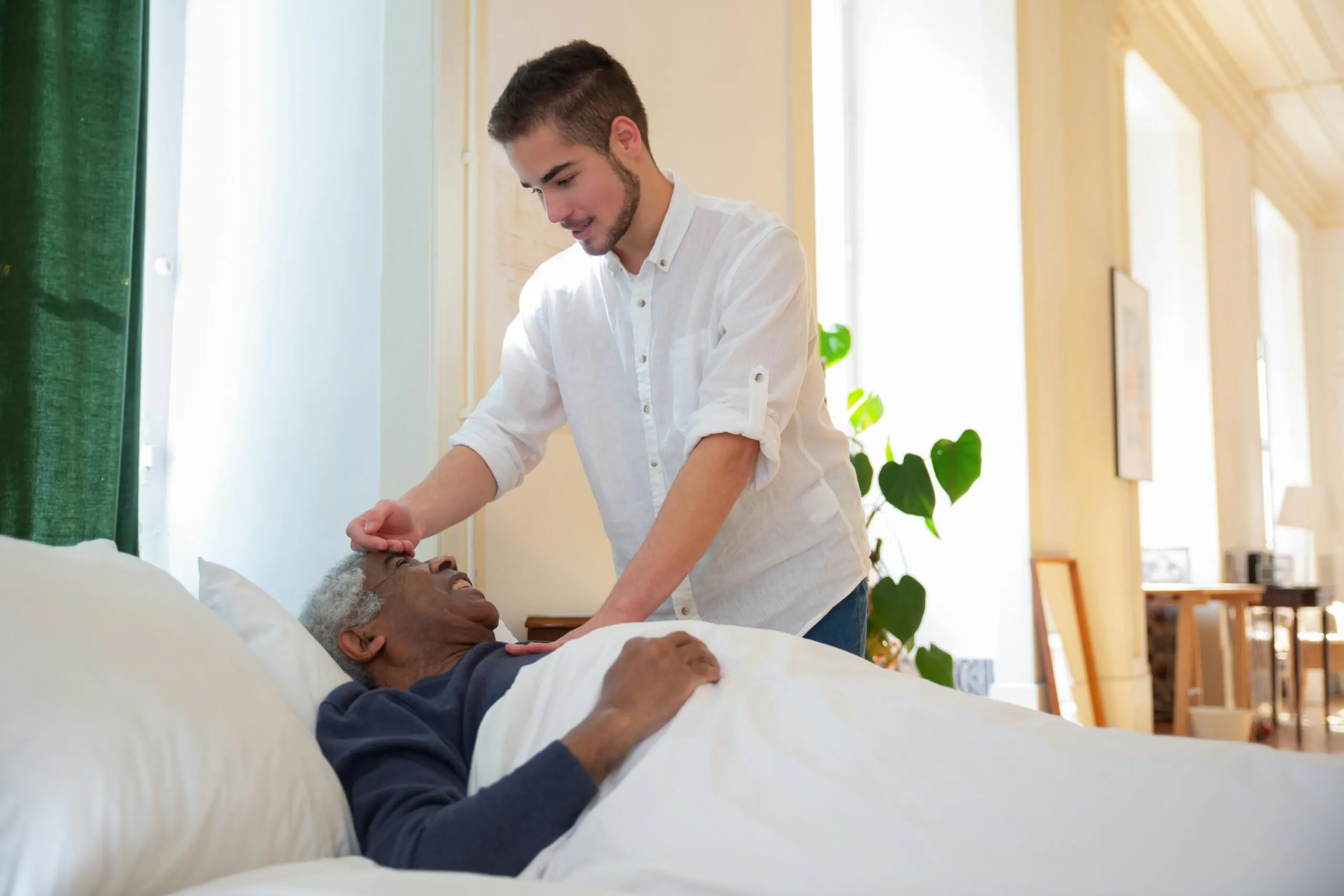Caregiver checking on an older man resting in bed (representative photo)