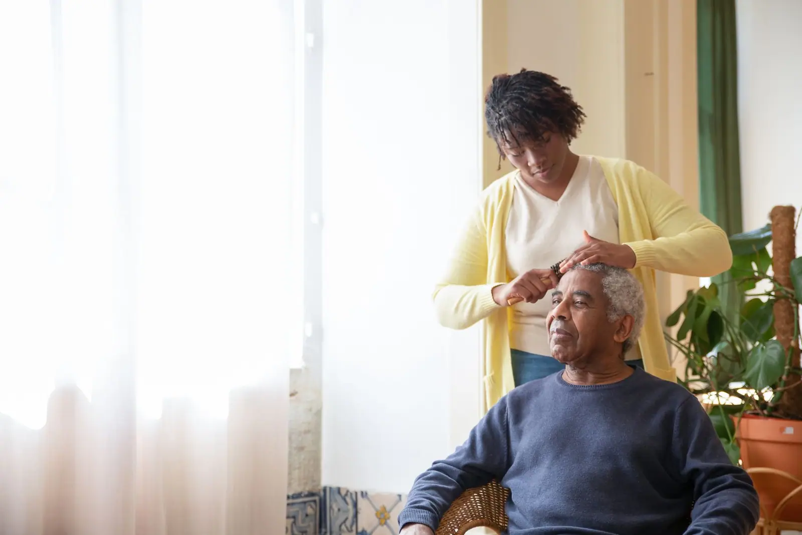 Caregiver brushing an older man’s hair in the morning light (representative photo)
