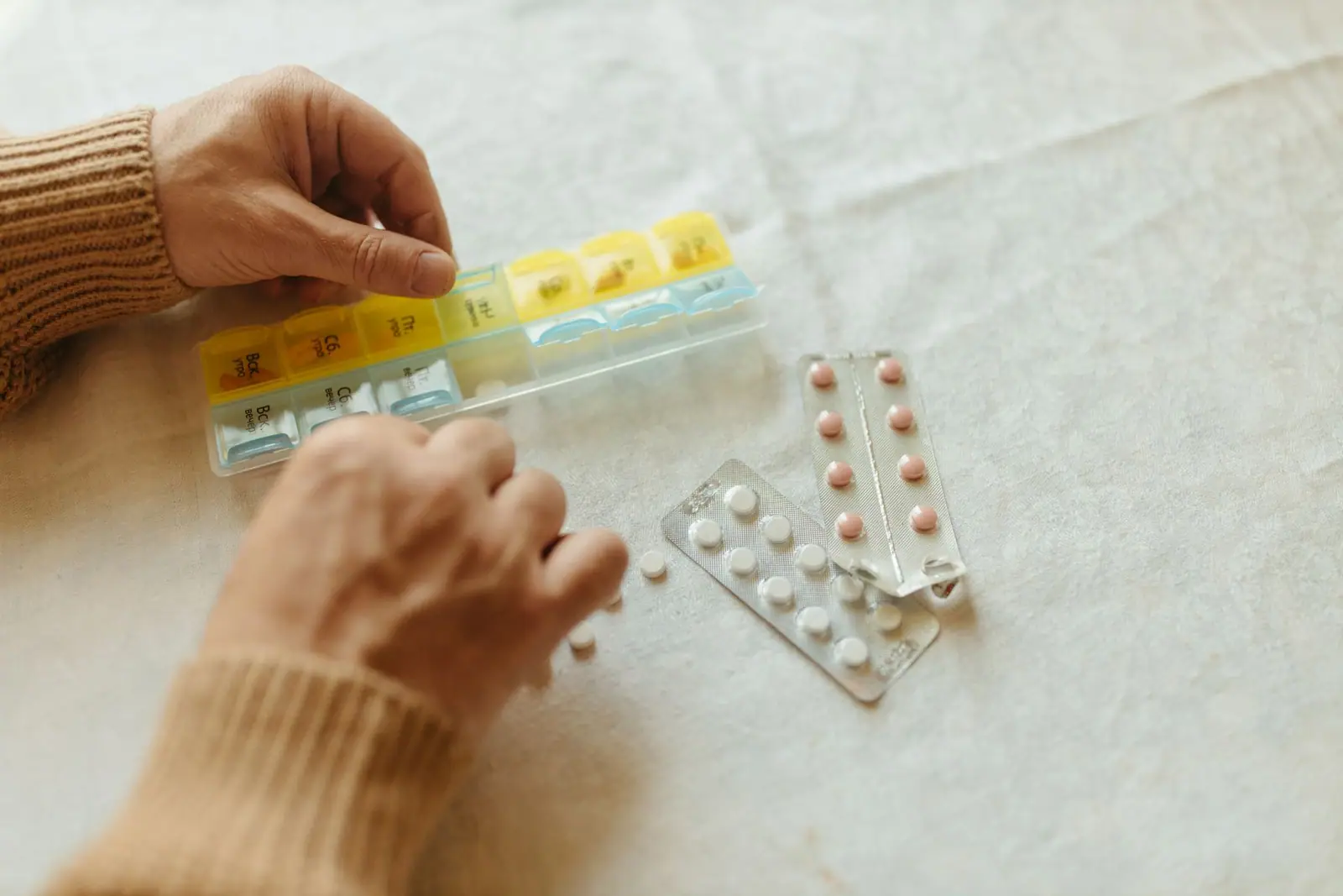 Hands pressing tablets from a blister pack into a pill organizer (representative photo)