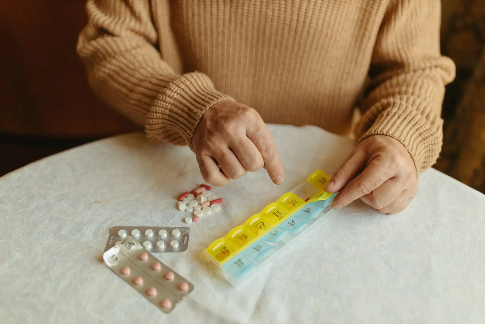 Hands sorting pills into a weekly pill organizer (representative photo)
