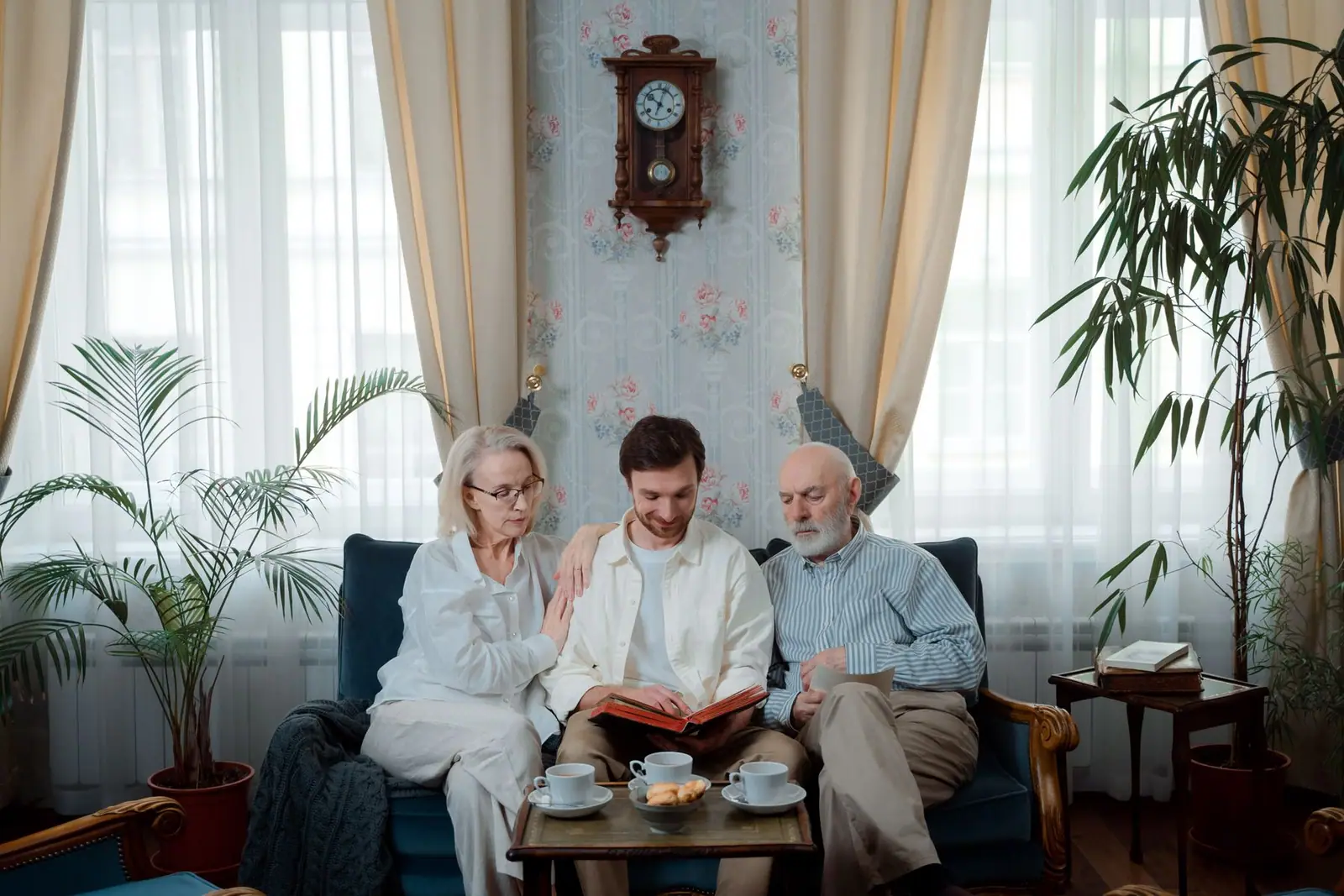 Older couple and their adult son looking through a photo album on a sofa (representative photo)