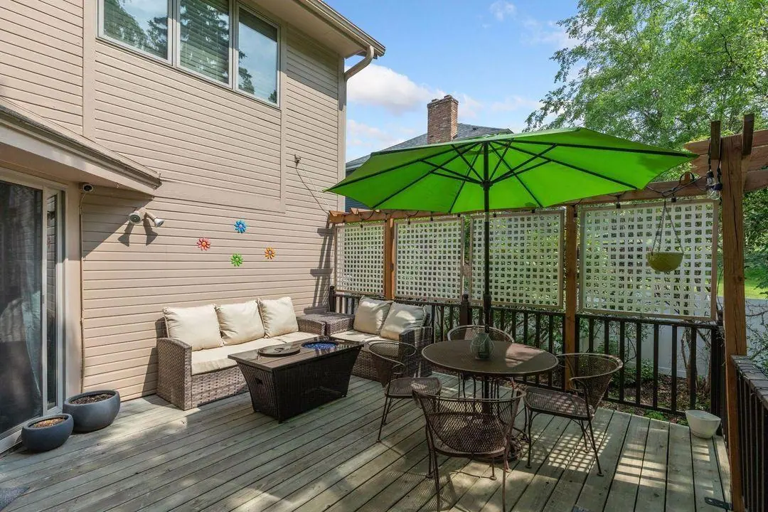 Wood deck with outdoor sofa, dining set and green umbrella behind the Burnsville home